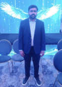 Man in a blazer standing on a stage with glowing angel wings backdrop