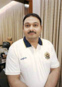 Man in white polo shirt with mustache, standing indoors near curtains