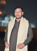 Man in dark kurta with beige shawl, standing outdoors at night