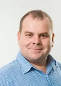 Portrait of a smiling man in a blue striped shirt on a light background
