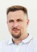 Portrait photo of a man with short hair and a goatee in a white polo shirt