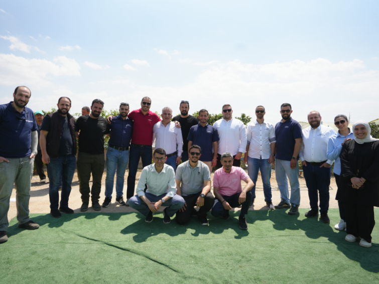 Group photo of men standing and kneeling on a green field under a blue sky