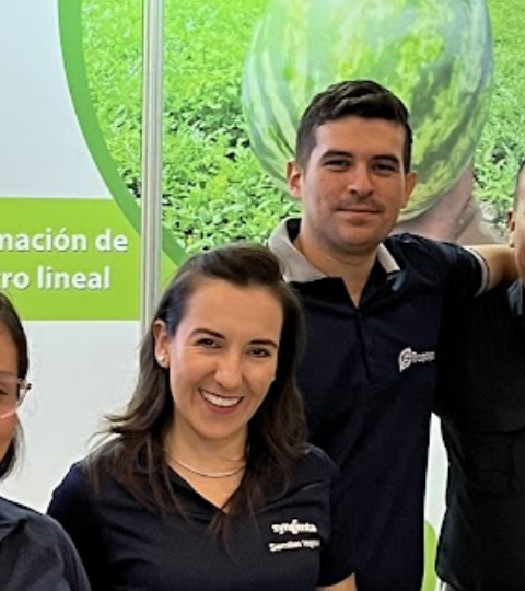Group of seven smiling people posing indoors at a conference booth
