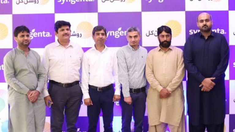 Five men standing in front of a purple-and-white sponsor backdrop at an event