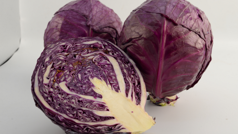 Whole and halved purple cabbage on a white surface