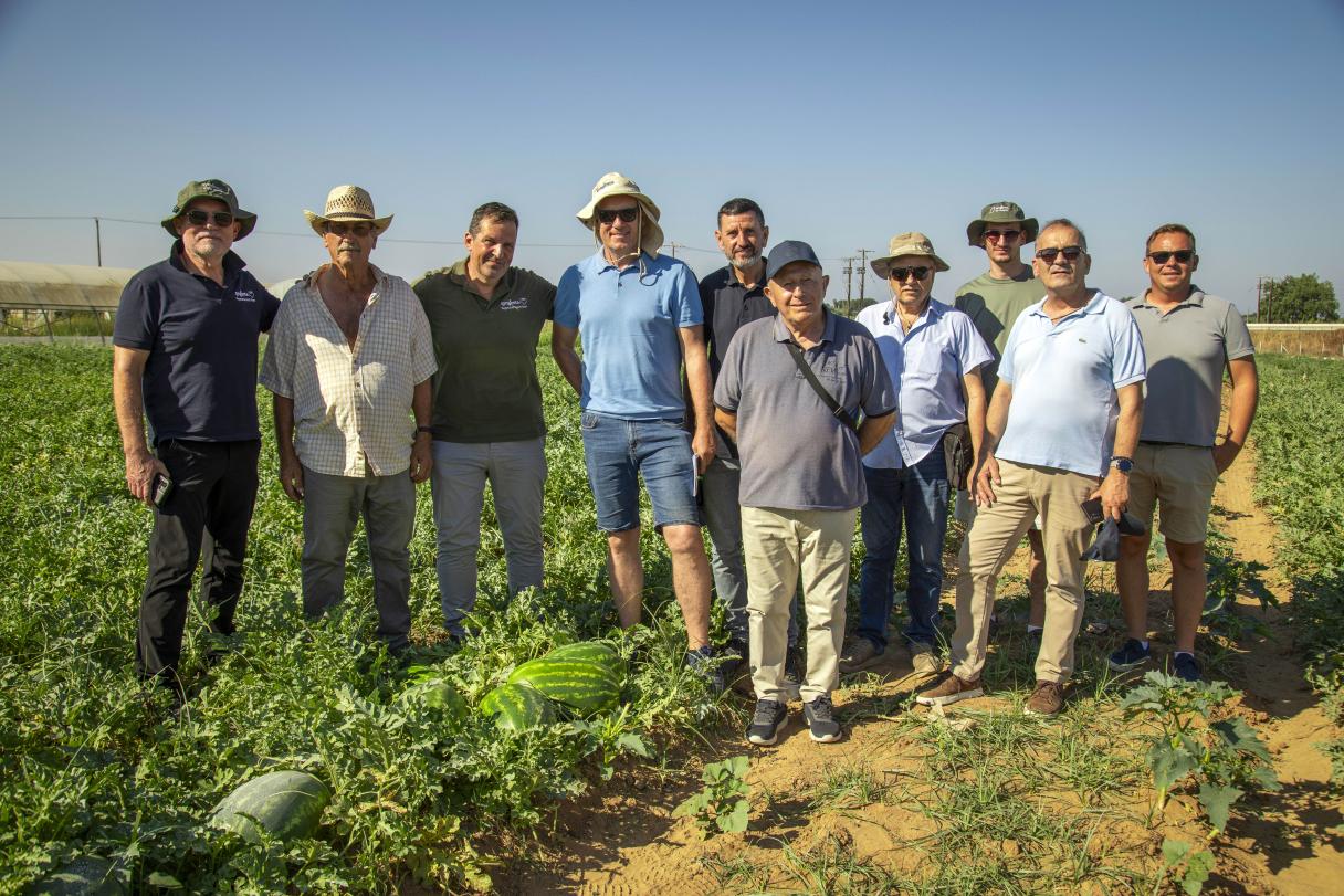 Group of farm workers standing in a green field under a clear blue sky